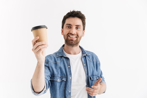 Portret van een knappe, bebaarde man met vrijetijdskleding die geïsoleerd staat en afhaalkoffie drinkt