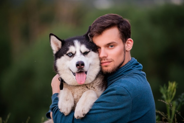 Portret van een knappe jonge man en zijn hond Siberische Husky in de natuur