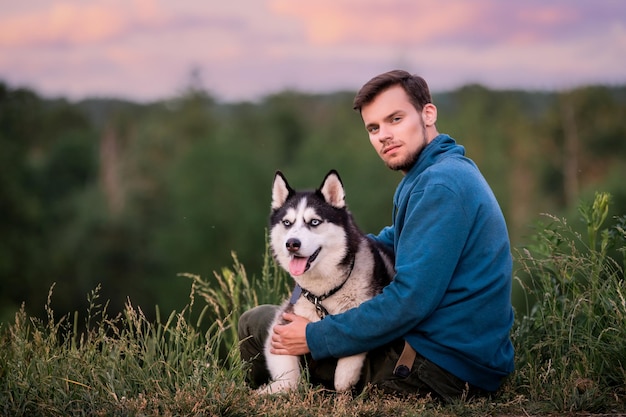 Portret van een knappe jonge man en zijn hond Siberische Husky in de natuur