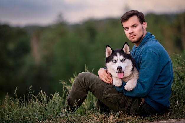 Portret van een knappe jonge man en zijn hond Siberische Husky in de natuur