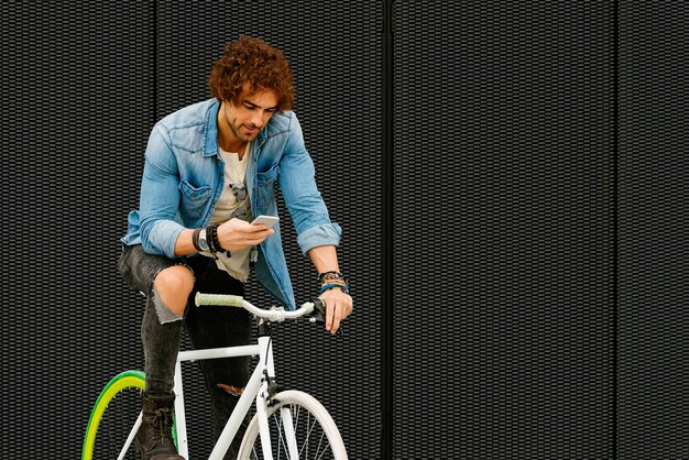 Portret van een knappe jongeman die lacht wanneer hij zijn mobiel op straat gebruikt.