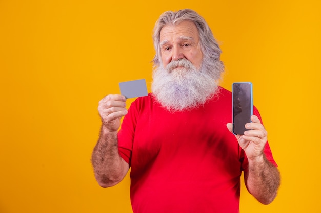 Portret van een knappe kerstman met creditcard en smartphone met een leeg scherm voor tekst in zijn hand.