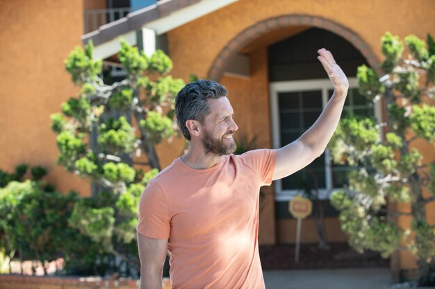 Portret van een knappe man die buiten een nieuw huis staat