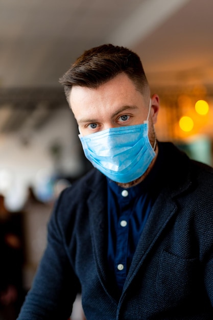 Portret van een knappe man in modekleren en gezichtsmasker op. Hoofd en schouders portret met onscherpe achtergrond. Detailopname.