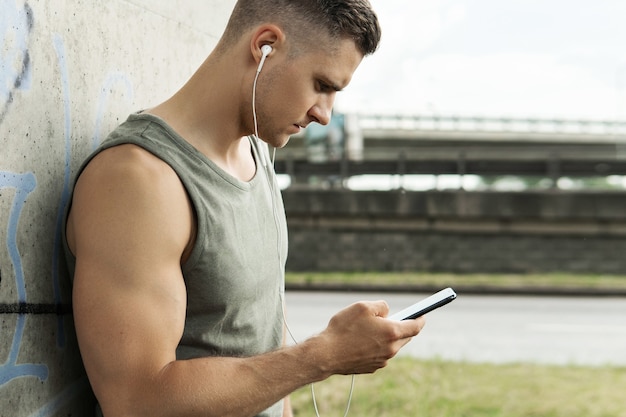 Portret van een knappe man met een koptelefoon. Muziek luisteren tijdens een fitnesstraining op straat.