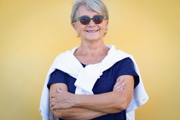 Portret van een knappe oudere vrouw die buiten tegen een gele muur staat