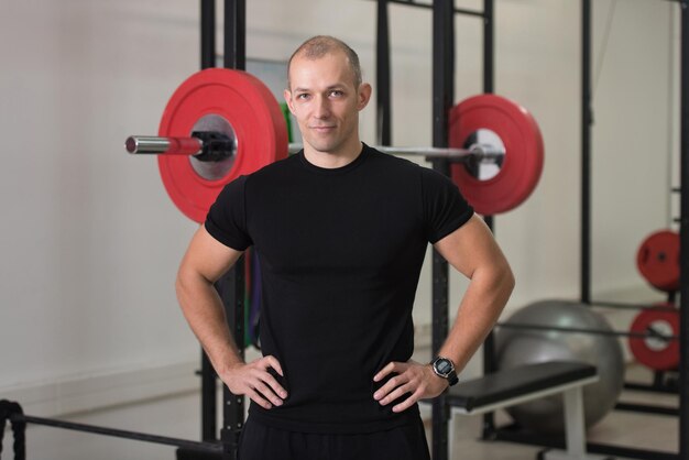 Portret van een knappe personal trainer die sportkleding draagt in een sportschool die sterk staat