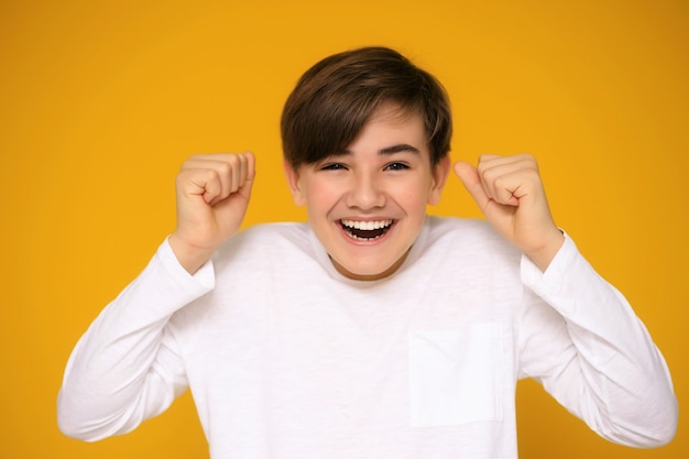 Portret van een knappe tiener 12-13 jaar oud op een gele achtergrond.