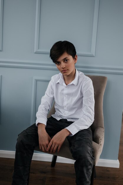 Foto portret van een knappe tiener die binnen op de stoel zit