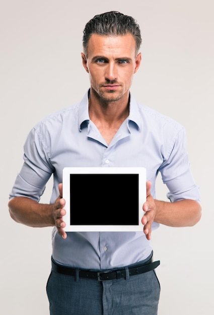 Portret van een knappe zakenman die het lege geïsoleerde scherm van de tabletcomputer toont