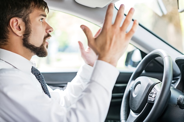 Portret van een knappe zakenman die in zijn auto rijdt