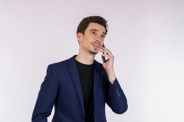 Portret van een knappe zakenman die via de mobiele telefoon praat en zich geïsoleerd op een witte achtergrond bevindt