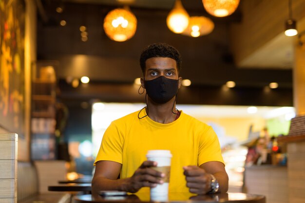 Portret van een knappe zwarte afrikaanse man met een geel t-shirt buiten in de stad in bangkok, thailand