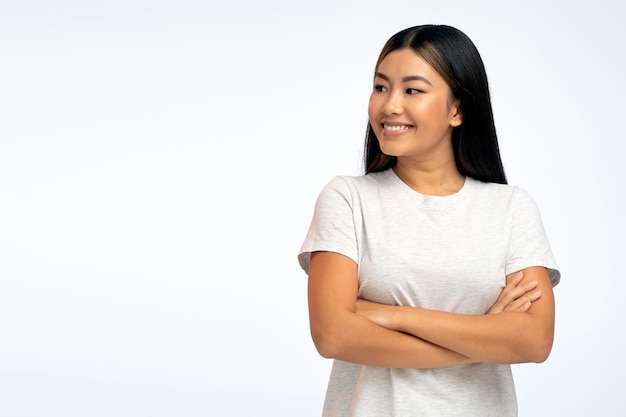 Portret van een kokette, speelse, mooie vrouw die wegkijkt en zich zorgeloos voelt poseren met gekruiste armen