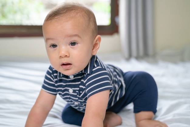 Portret van een kruipende baby op het bed in zijn kamer