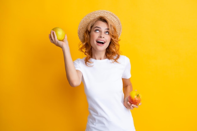 Portret van een lachend gelukkig meisje met appel geïsoleerd op gele achtergrond