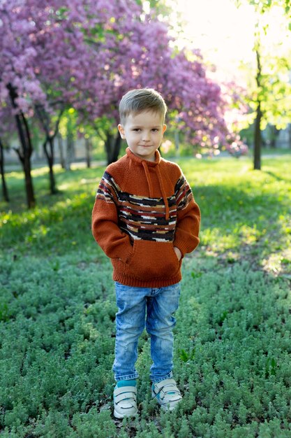 Portret van een lachend kind (happy boy) op de achtergrond van een bloeiende boom in het voorjaar.