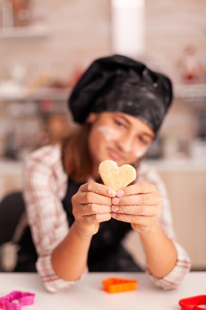 Portret van een lachend kind met een schort dat traditioneel deeg vasthoudt