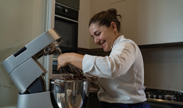 Portret van een lachende banketbakker die naar haar deeg kijkt in haar patisserie