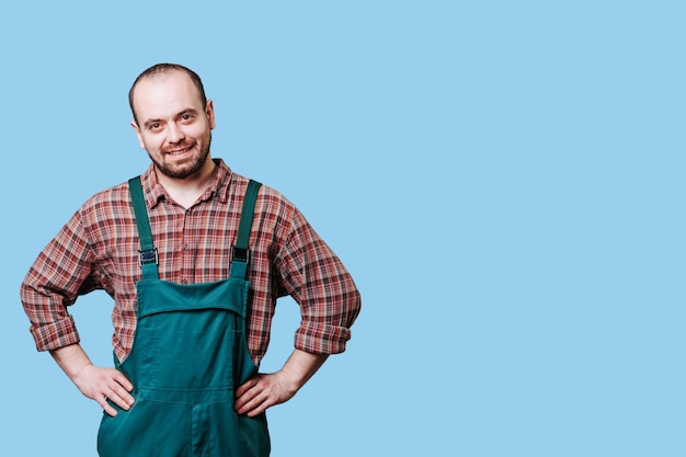 Portret van een lachende, bebaarde jonge werkman met armen op de heupen is de belichaming van positiviteit