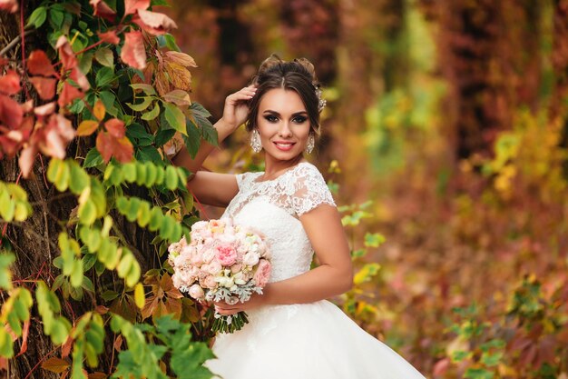 Portret van een lachende bruid tegen de achtergrond van een herfstbos Kleurrijke natuur