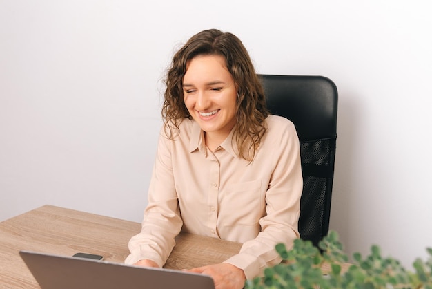 Portret van een lachende en vrolijke jonge blanke vrouw die op een laptop op kantoor werkt Goed nieuws