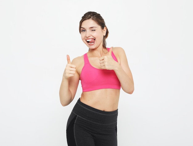 Portret van een lachende fitness vrouw in koptelefoon aan het trainen geïsoleerd op witte achtergrond