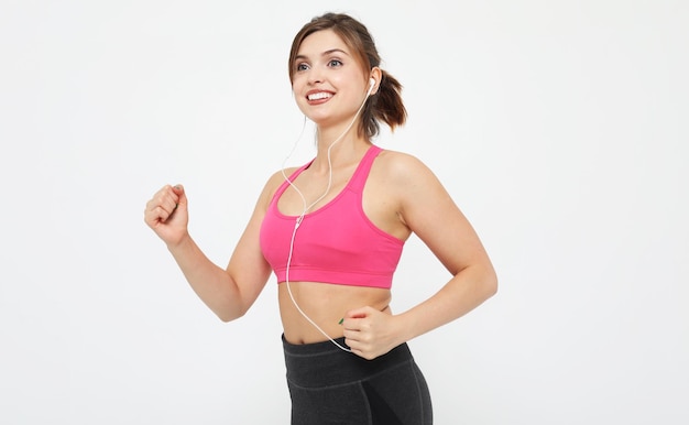 Portret van een lachende fitness vrouw in koptelefoon aan het trainen geïsoleerd op witte achtergrond