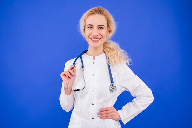 Portret van een lachende jonge vrouw arts op een blauwe achtergrond