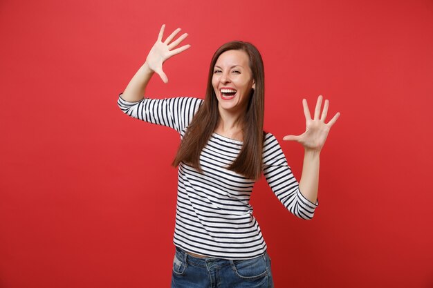 Portret van een lachende jonge vrouw in casual gestreepte kleding die staat en handen, vingers spreidt