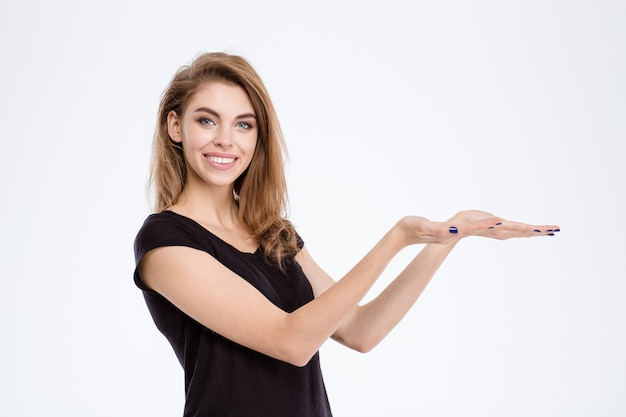 Portret van een lachende jonge vrouw met copyspace op de handpalmen geïsoleerd op een witte achtergrond