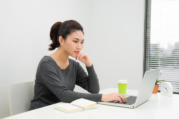 Portret van een lachende jonge zakenvrouw met laptop in een licht kantoor