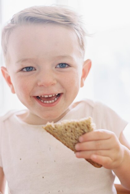 Portret van een lachende jongen die een broodje eet