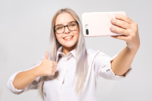 Portret van een lachende leuke vrouw in glazen selfie foto maken op smartphone