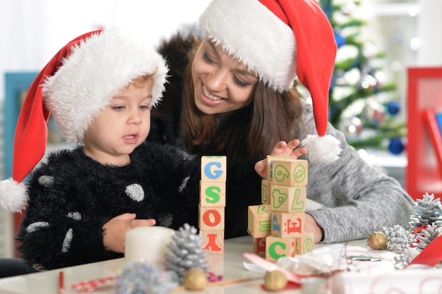 Portret van een lachende moeder en een schattig dochtertje dat zich thuis voorbereidt op Kerstmis met kerstmutsen