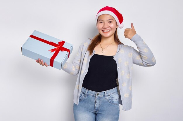 Portret van een lachende mooie jonge Aziatische vrouw in een kerstman hoed met als voor cadeau Kerst gebaar geïsoleerd op witte studio achtergrond Merry Christmas Concept