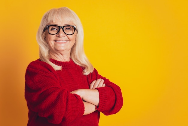 Portret van een lachende oude vrouw geïsoleerd tegen gele achtergrond