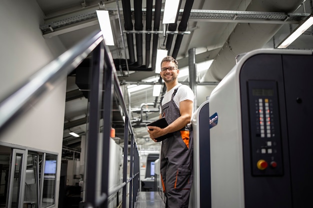 Portret van een lachende printer die bij de drukmachine staat