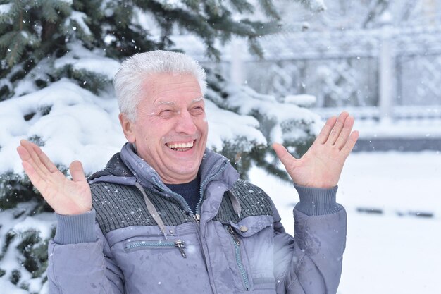 Portret van een lachende senior man die in de winter buiten staat