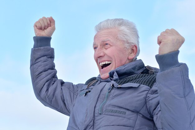 Portret van een lachende senior man die in de winter buiten staat