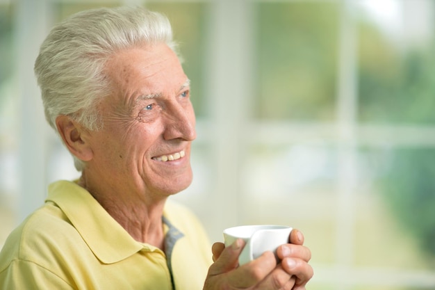 Portret van een lachende senior man die koffie drinkt