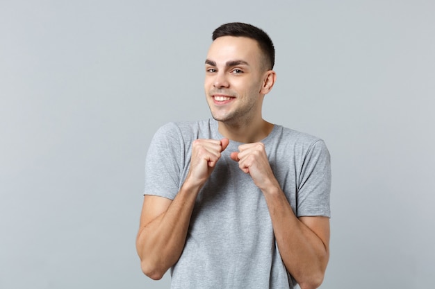 Portret van een lachende vrolijke jongeman in vrijetijdskleding en gebalde vuisten