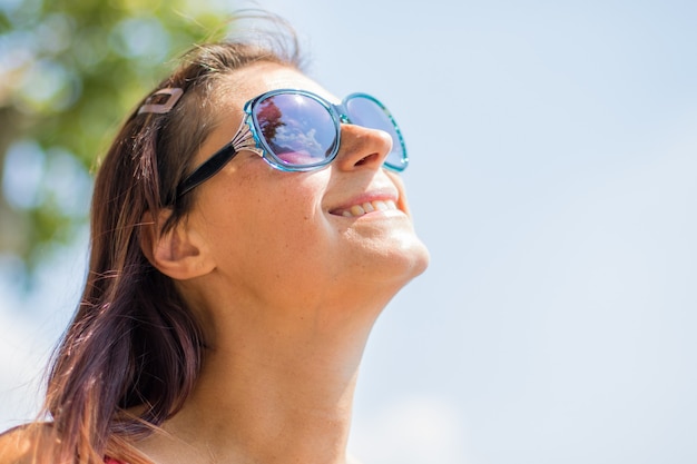 Portret van een lachende vrouw met hoed aan het meer