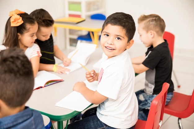 Portret van een Latijnse kleuter die aan een schrijfopdracht werkt en geniet van school