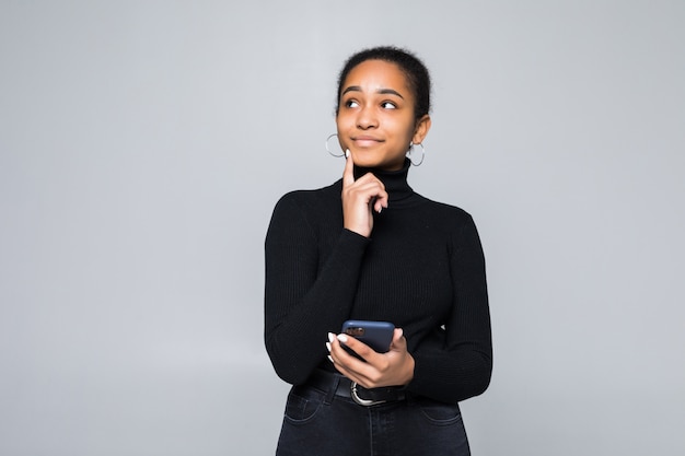 Portret van een Latijnse vrouw die mobiele telefoon houdt en weg met hand op haar kin kijkt