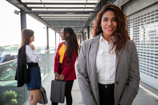 Portret van een latina zakenvrouw met haar collega's achter haar die een gesprek voeren