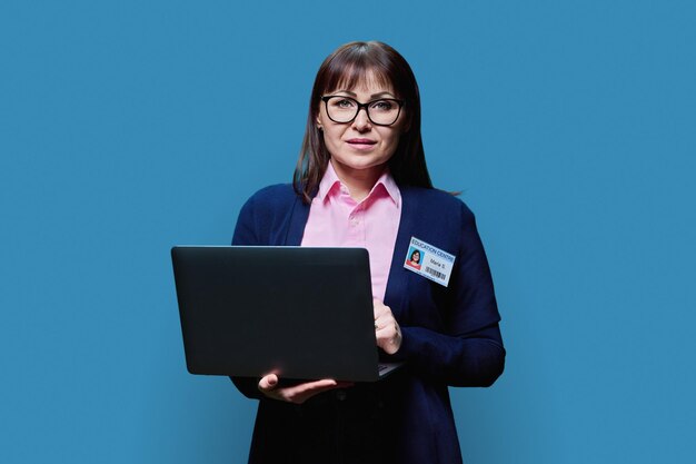 Portret van een lerares met een laptop op een blauwe achtergrond