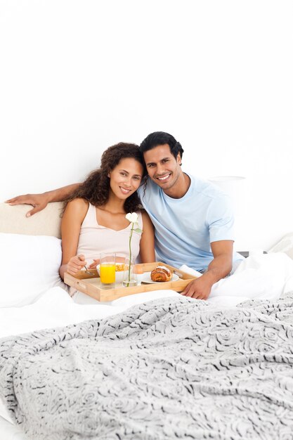 Portret van een leuk paar dat ontbijt in hun bed heeft