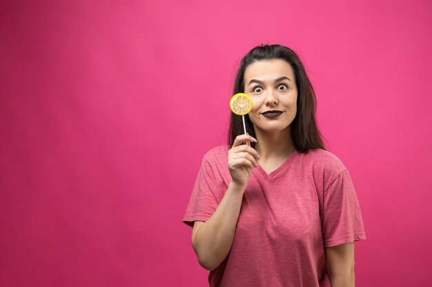 Portret van een lieve, mooie, vrolijke vrouw met steil bruin haar met een lolly bij de ogen