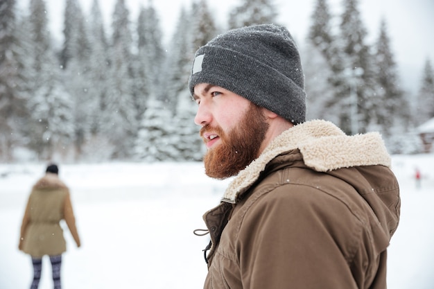 Portret van een man die buiten wegkijkt met sneeuw op backgorund